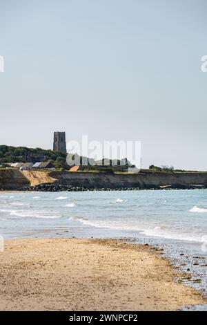 HAPPISBURGH, ENGLAND - 16. JUNI 2023: Blick auf Happisburgh und St. Mary the Virgin Church, Norfolk, England, am Strand an einem sonnigen Frühlingstag Stockfoto