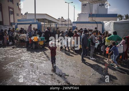 Rafah, Gazastreifen, Palästinensische Gebiete. März 2024. Die Palästinenser sammeln Wasser aus einer Wassertankstelle, wo die Menschen aufgrund des Krieges unter Wasserknappheit leiden. Die Gesamtzahl der Todesopfer in Gaza hat seit Beginn des Krieges am 7. Oktober 30.000 überschritten, so das Gesundheitsministerium des Streifens. Auch in dieser Woche wurden weitere Details über eine mögliche neue Waffenstillstandsvereinbarung bekannt, die vor dem Ramadan beginnen könnte, bis weitere Verhandlungen zwischen Israel, Hamas und ausländischen Mittlern abgeschlossen sind. (Kreditbild: © Saher Alghorra/ZUMA Press Wire) NUR REDAKTIONELLE VERWENDUNG! Nicht für kommerzielle ZWECKE! Stockfoto