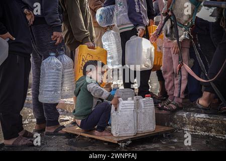 Rafah, Gazastreifen, Palästinensische Gebiete. März 2024. Die Palästinenser sammeln Wasser aus einer Wassertankstelle, wo die Menschen aufgrund des Krieges unter Wasserknappheit leiden. Die Gesamtzahl der Todesopfer in Gaza hat seit Beginn des Krieges am 7. Oktober 30.000 überschritten, so das Gesundheitsministerium des Streifens. Auch in dieser Woche wurden weitere Details über eine mögliche neue Waffenstillstandsvereinbarung bekannt, die vor dem Ramadan beginnen könnte, bis weitere Verhandlungen zwischen Israel, Hamas und ausländischen Mittlern abgeschlossen sind. (Kreditbild: © Saher Alghorra/ZUMA Press Wire) NUR REDAKTIONELLE VERWENDUNG! Nicht für kommerzielle ZWECKE! Stockfoto