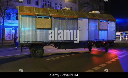 Berlin, Deutschland. März 2024. Der Bauanhänger, der im Rahmen der Fahndung der gesuchten Ex-RAF-Terroristen Staub und Garweg beschlagnahmt wurde, wird von einem THW-Lkw abgeschleppt. Am frühen Montagmorgen ließ die Polizei den Bauwagen von einem linken Alternativgelände in Berlin entfernen. Quelle: Dominik Totaro/dpa/Alamy Live News Stockfoto