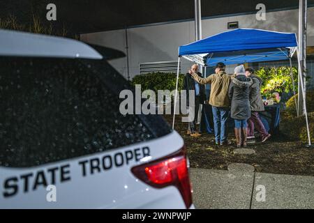 Marysville, Usa. März 2024. Die Familie von Trooper Christopher Gadd steht in einer düsteren Umgebung neben dem sich erweiternden Denkmal, das zu seinen Ehren im Hauptquartier der Washington State Patrol in Marysville errichtet wurde. Die Kollision, die in der Nähe der 136th Street Northeast kurz vor 3 Uhr morgens stattfand, löste eine sofortige Reaktion der Sheriffs von Snohomish County aus. Der Soldat, genannt Christopher Gadd, im Alter von 27 Jahren, erlag tragischerweise seinen Verletzungen am Tatort. Gadd, der 2,5 Jahre bei der Staatspatrouille gedient hatte, war in Marysville stationiert. Quelle: SOPA Images Limited/Alamy Live News Stockfoto