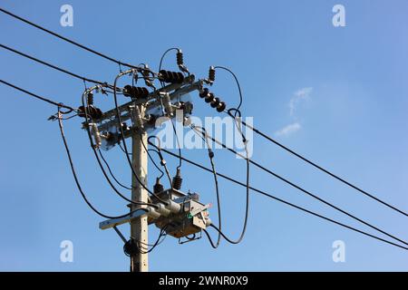 Hochspannungsdrähte angeschlossen Hochspannungstransformator am Pol gegen blauen Himmel montiert, Nahaufnahme Stockfoto