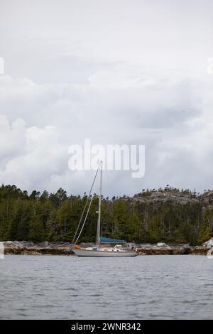 Ein wunderschönes Segelboot in einem abgelegenen Ankerplatz mit Bergen im Hintergrund, Zentralküste von British Columbia, Kanada Stockfoto