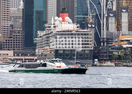 Die Sydney rivercat Fähre mit der MV Nicole Livingstone passiert das Heck des Kreuzfahrtschiffs Queen Victoria, das in Sydney Cove, NSW, Australien, 2024 vor Anker liegt Stockfoto