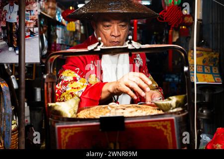 Thailand, 10. Februar 2024: Chakngeaw Chinese Village. Ein Verkäufer sucht nach einem Zongzi, einem klebrigen Reis mit herzhaften Füllungen in Bambusblättern. Stockfoto