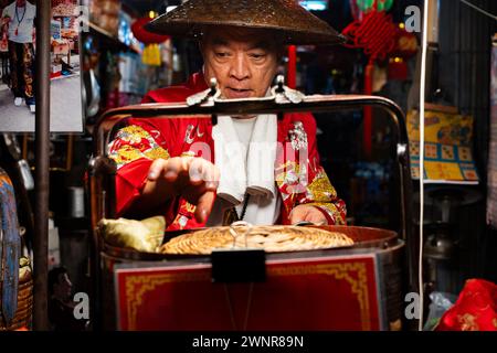 Thailand, 10. Februar 2024: Chakngeaw Chinese Village. Ein Verkäufer sucht nach einem Zongzi, einem klebrigen Reis mit herzhaften Füllungen in Bambusblättern. Stockfoto