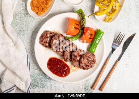 Gegrillte Fleischbällchen. Mit Tomaten, Paprika, Vorspeisen und Spezialsauce. Türkische Fleischbällchen auf einem Teller Stockfoto