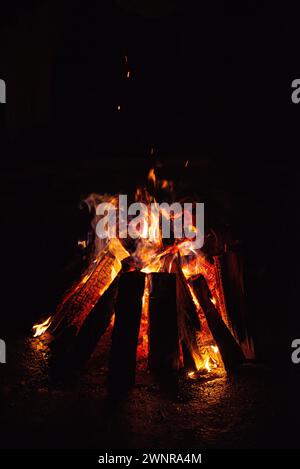 Ein lebhaftes Lagerfeuer brennt hell gegen die dunkle Nacht, Funken steigen in den Himmel. Stockfoto