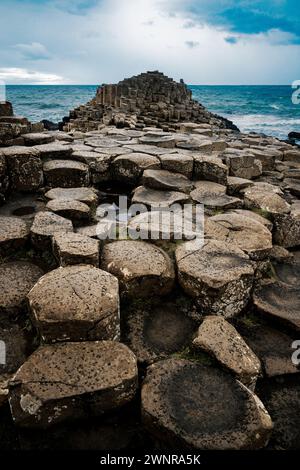 Ein dramatisches Landschaftsfoto mit dem Giant's Causeway, einem UNESCO-Weltkulturerbe in Nordirland. Das Bild zeigt das ikonische sechseckige Stockfoto