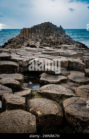 Ein dramatisches Landschaftsfoto mit dem Giant's Causeway, einem UNESCO-Weltkulturerbe in Nordirland. Das Bild zeigt das ikonische sechseckige Stockfoto