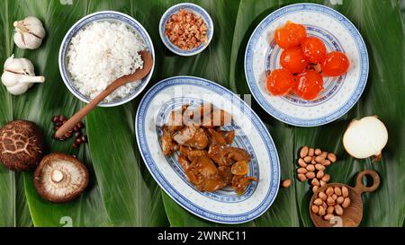 Zongzi Zutatenzubereitung, köstliches traditionelles Reisknödelnahrungsmittel für Drachenboot Duanwu Festival über Bambusblatt Bacang Wrapping, Top View. Stockfoto
