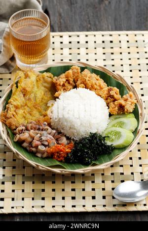 Nasi Rames oder indonesischer Mix Reis, gedämpfter Reis mit verschiedenen Beilagen. Serviert mit Tee Stockfoto