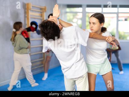 Teenager-Mädchen üben Handabsatz-Schlag im Kinn während des Scheinkampfes mit dem Jungen Stockfoto
