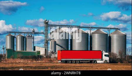 Auflieger mit rotem Anhänger vor Silos der landwirtschaftlichen Getreideverarbeitungsanlage, selektiver Fokus Stockfoto