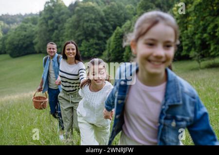 Die Familie läuft durch den Wald, geht durch die Wiese. Pilze sammeln, Kräuter sammeln, Blumen im Korb sammeln, Futter sammeln. Konzept des familiären ökologischen Hobbys in Stockfoto