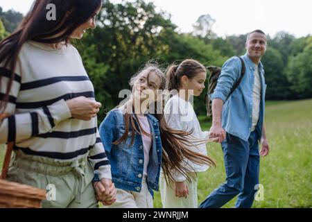 Die Familie läuft durch den Wald, geht durch die Wiese. Pilze sammeln, Kräuter sammeln, Blumen im Korb sammeln, Futter sammeln. Konzept des familiären ökologischen Hobbys in Stockfoto