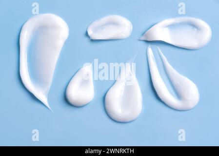 Weiße kosmetische Creme-Lotion-Muster-Abstrich-Muster auf blauem Hintergrund. Satz von Streichungen für leichte Gelkosmetika. Stockfoto