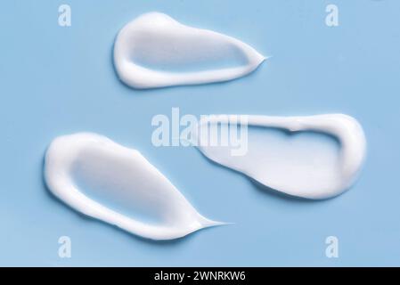 Weiße kosmetische Creme-Lotion-Muster-Abstrich-Muster auf blauem Hintergrund. Satz von Streichungen für leichte Gelkosmetika. Stockfoto