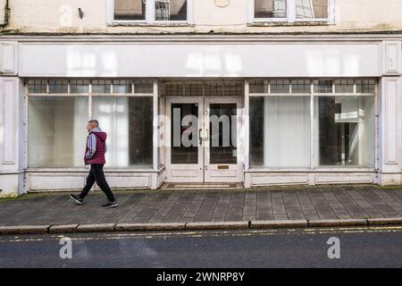 Ein Mann, der an einem leeren geschlossenen Laden in der Fore Street im Stadtzentrum von Bodmin in Cornwall in Großbritannien vorbeigeht. Stockfoto