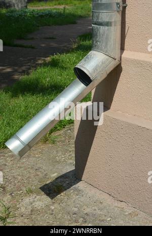 Nahaufnahme auf Gipswänden Fundamentplatte in Metalldachrinne downspout Rohr nach Renovierung der Hausfassade. Stockfoto