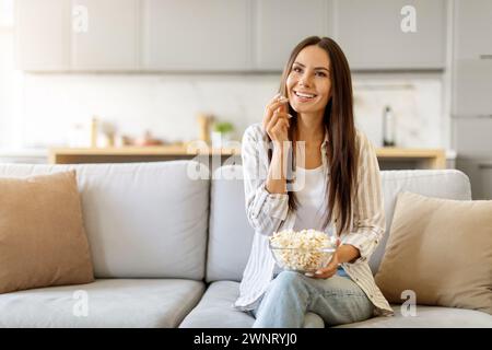 Schöne Junge Frau, Die Zu Hause Popcorn Isst, Während Sie Sich Auf Der Couch Entspannt Stockfoto