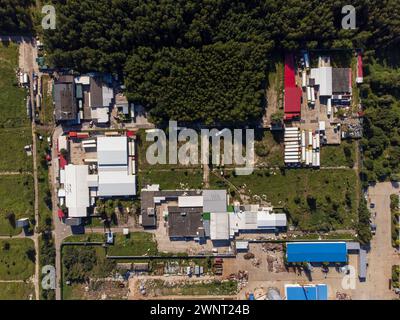 Ein Luftbild, das einen weitläufigen Industriekomplex zeigt, umgeben von Grün unter klarem Himmel. Stockfoto