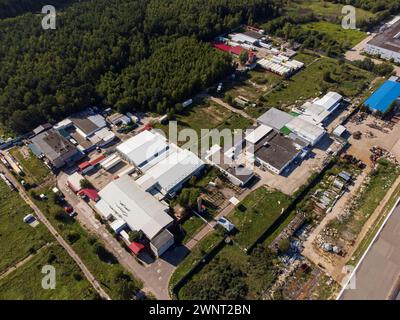 Ein Luftbild, das einen weitläufigen Industriekomplex zeigt, umgeben von Grün unter klarem Himmel. Stockfoto