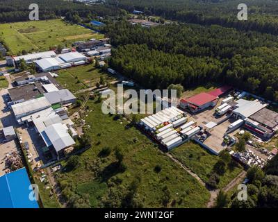Ein Luftbild fängt die weitläufige Weite eines industriellen Fabrikkomplexes ein, der sich einer üppigen grünen Landschaft unter klarem Himmel gegenüberstellt. Stockfoto