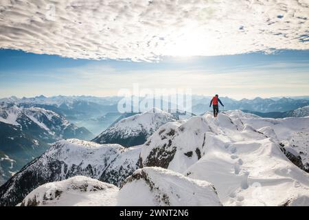 Ein Wanderer mit Rucksack steht im Winter auf dem Gipfel eines Berges Stockfoto