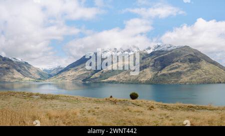 Bergsee-Landschaft mit trockenem Gras im Vordergrund und blauem Himmel Stockfoto