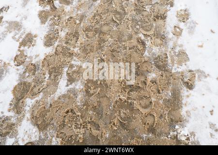 Viele Fußabdrücke von Schuhen und Stiefeln auf dem verschneiten Bürgersteig. Winter in der Stadt. Nasses Wetter und Temperaturen unter dem Gefrierpunkt. Wettervorhersage. Eis, weißer Schnee Stockfoto
