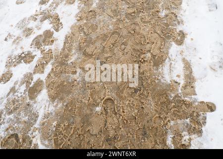 Viele Fußabdrücke von Schuhen und Stiefeln auf dem verschneiten Bürgersteig. Winter in der Stadt. Nasses Wetter und Temperaturen unter dem Gefrierpunkt. Wettervorhersage. Eis, weißer Schnee Stockfoto