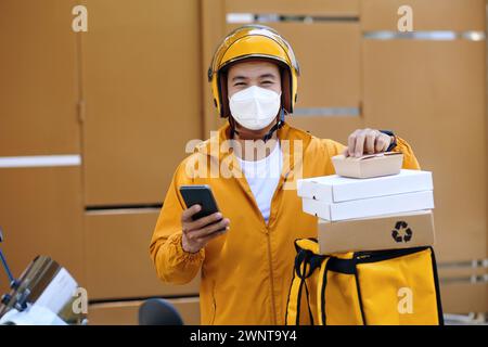 Porträt eines Mannes, der bei der Lieferung von Lebensmitteln an Kunden eine Schutzmaske trägt Stockfoto