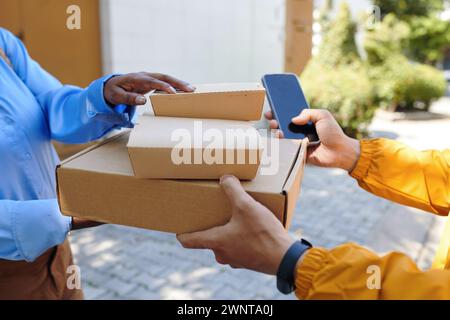 Hände des Lieferers, der Kisten mit Lebensmitteln an den Kunden überreicht Stockfoto