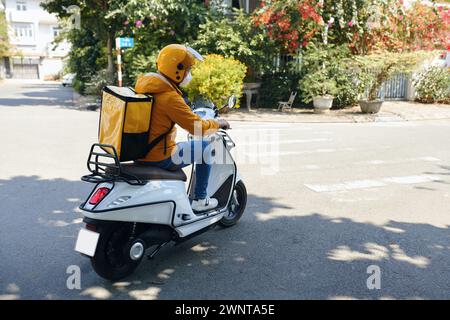 Liefermann in gelber Uniform fahrend Motorrad Stockfoto