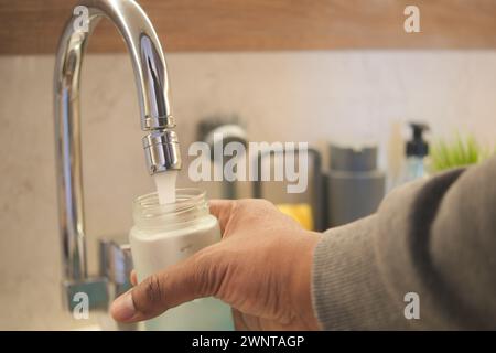 Füllen einer Flasche mit Wasser aus einem Wasserhahn mit Handgesten Stockfoto