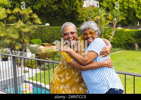 Ältere afroamerikanische Frau und ältere birassische Frau teilen sich eine freudige Umarmung im Freien Stockfoto