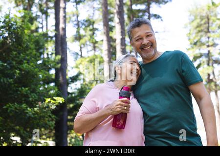 Ein hochrangiges Paar genießt einen sonnigen Tag im Freien, während die Frau eine Wasserflasche hält Stockfoto