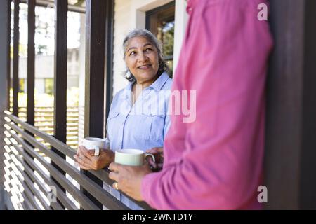 Ältere Frau mit grauen Haaren hält eine Kaffeetasse und lächelt warm Stockfoto