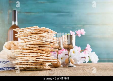 Passover-Feier-Konzept. Matzah, roter Koscher und Nussbaum auf Holztisch im Vintage-Stil vor Frühlingsblüten-Baumgarten und Blumenlandschaft mit Stockfoto