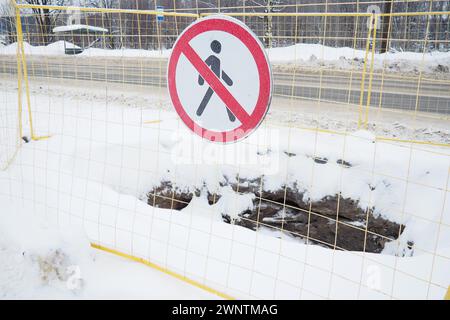 Kein Durchgangsschild, nicht passieren. Der Mann hat eine rote Linie durchgestrichen. Rundes Verkehrsverbot. Verboten. Ein Loch, das in den Boden gegraben wurde, umgeben von einem Metall Stockfoto