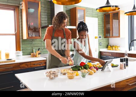 Ein vielseitiges Paar, ein junger Kaukasier und ein afroamerikanisches Mädchen kochen zusammen in einer modernen Küche Stockfoto