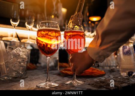 Der Barkeeper macht zwei Gläser Cocktail Aperol Spritz an der Bar und fügt frische Orangenscheiben hinzu. Typisch italienisches alkoholisches Getränk, Aperitif mit Stockfoto