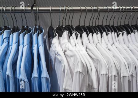 Blau-weiße Hemden an Kleiderbügeln hängen am Regal Stockfoto