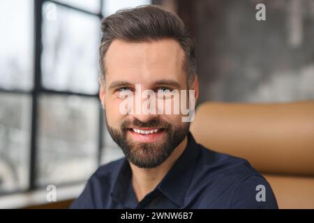 Porträt eines glücklichen jungen Geschäftsmannes, der ein schickes Hemd trägt und in die Kamera schaut. Erfolgreicher männlicher Mitarbeiter lächelt Stockfoto