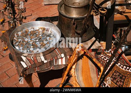 Alte Münzen in einem Metalltablett, rostiger alter Kessel und Töpfe, Schlüsselanhänger, Teppich und andere Waren in einem Geschäft am Basar. Stockfoto