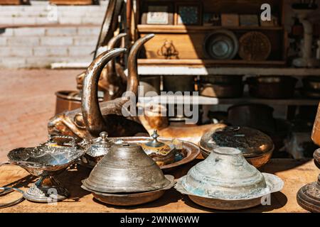 Vintage-Bronzestatue, Mörser, Silber- und Kupferplatten, Rahmen und andere Ornamente auf der Ablagefläche in einem Geschäft am Basar. Stockfoto