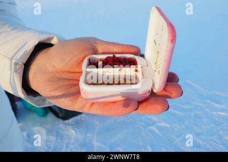 Lebender Blutwurm in einem Kistenbehälter. Rote Würmer für Winterfischen. Eine Frau hält eine Kiste mit Blutwürmern in den Händen und bereitet sich darauf vor, einen Wurm auf einen zu legen Stockfoto