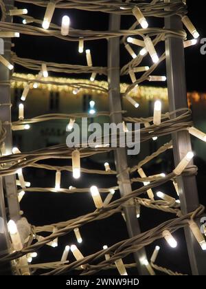 Straßengirlanden mit weißen kleinen Lampen am Abend auf einer Stadtstraße. Festliche Neujahrsdekoration Stadtstraßen und Parks Stockfoto