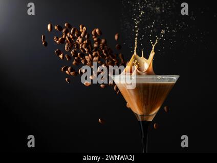 Espresso Martini-Getränk mit Spritzern und fallenden Kaffeebohnen auf schwarzem Hintergrund. Kopierbereich. Stockfoto